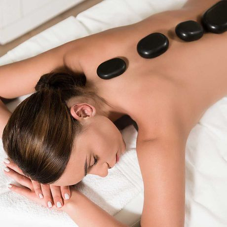 Schöne junge Frau bei einer Hot-Stone-Massage im Spa-Salon